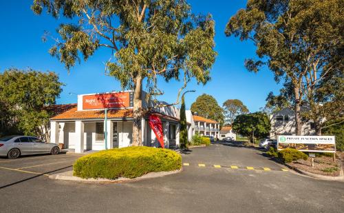 a red brick building with a tree in front of it at Nightcap at Ferntree Gully Hotel Motel in Fern Tree Gully