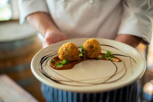 a person holding a plate with food on it at Oaks Cypress Lakes Resort in Pokolbin