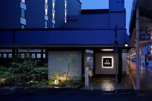 Hotel Resol Kyoto Kawaramachi Sanjo في كيوتو: مبنى عليه لوحة على شجرة