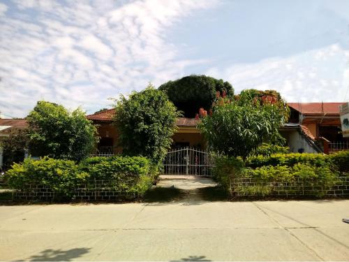 une maison avec des buissons et une clôture devant elle dans l'établissement Backpacker Kitara House, à Tarapoto