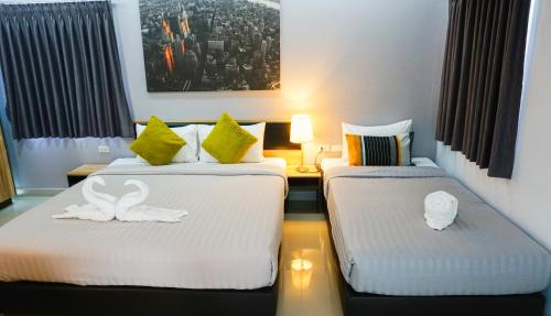 two beds in a hotel room with towels on them at Zada Residence in Nakhon Ratchasima
