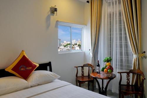 a bedroom with a bed and a window with a table at Full House Hotel in Nha Trang