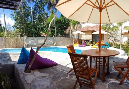 a table and chairs with an umbrella next to a pool at ZiFa Mandalika in Kuta Lombok