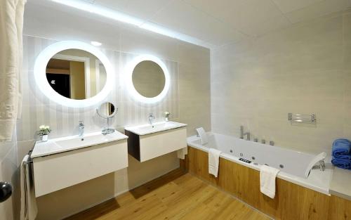 a bathroom with two sinks and a tub and a mirror at Hotel Salobreña Suites in Salobreña