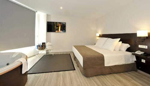 a hotel room with a bed and a bath tub at Hotel Salobreña Suites in Salobreña