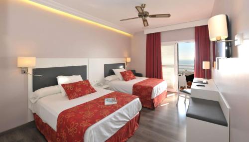 a hotel room with two beds and a balcony at Hotel Salobreña Suites in Salobreña