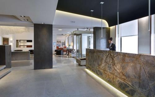 a man sitting at a counter in a lobby at Best Western Plus Hotel Bologna in Mestre