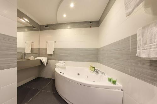 a white bathroom with a tub and a sink at Best Western JFK Hotel in Naples