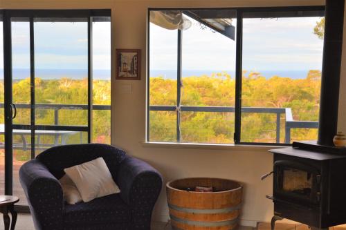 a living room with a chair and a barrel and windows at Surinam in Dunsborough