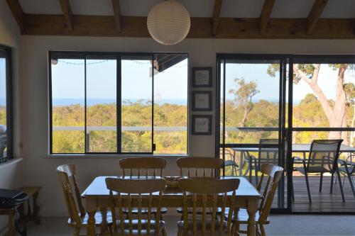 a dining room with a table and chairs and windows at Surinam in Dunsborough