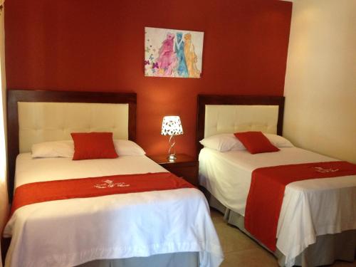 twee bedden in een kamer met rode muren bij Hotel Boutique Casa D' Luna in Choluteca