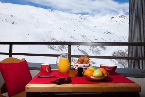 a table with a bowl of fruit and a glass of orange juice at Résidence Azureva Les Menuires in Les Menuires