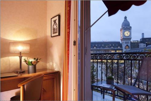 a room with a desk and a window with a clock tower at Hotel Terminus Lyon in Paris
