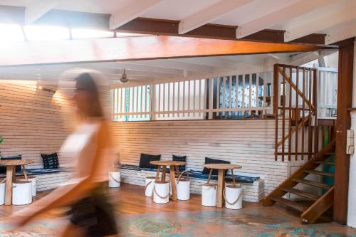 a woman walking through a room with tables and benches at Wake Up! Byron Bay in Byron Bay