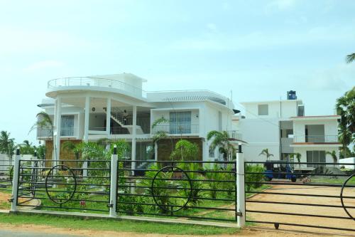 a white house with a fence in front of it at Sunstar Nilaveli in Trincomalee