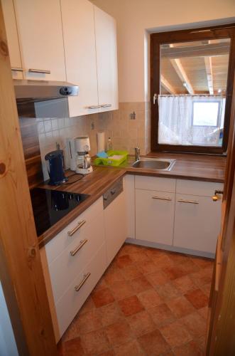 a kitchen with white cabinets and a sink and a window at Apartmenthaus Bader in Leutasch