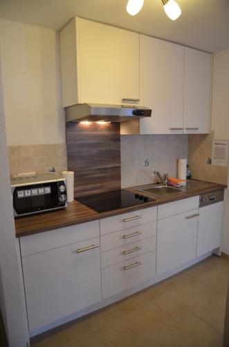 a kitchen with white cabinets and a microwave at Apartmenthaus Bader in Leutasch