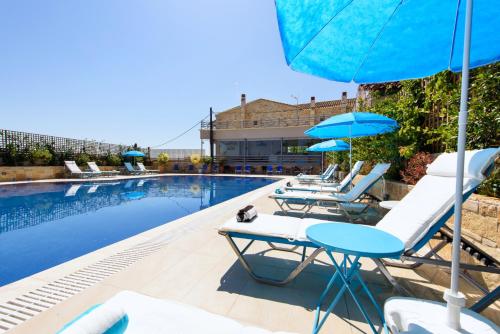 a pool with lounge chairs and umbrellas next to a swimming pool at Angelo Del'Arte Estate in Corfu Town