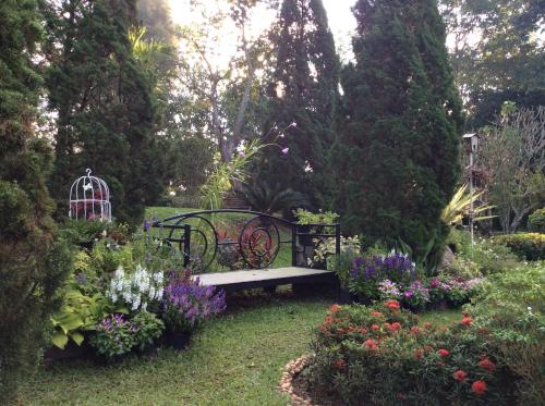 a bench in a garden with flowers and plants at Baan JaoKorKluay บ้านเจ้ากอกล้วย in Chiang Rai