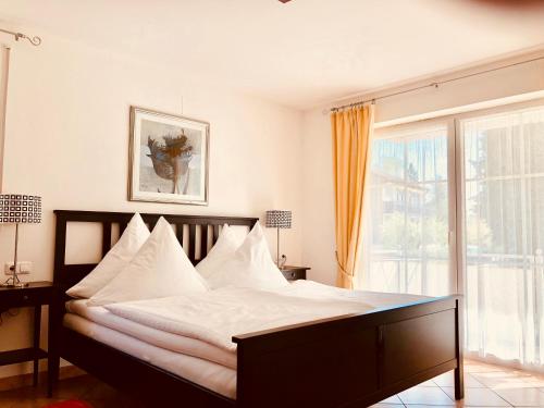 Schlafzimmer mit einem Bett mit weißer Bettwäsche und einem Fenster in der Unterkunft Ferienwohnungen Birkenhof in Bad Wörishofen