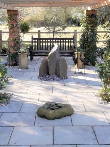 a stone patio with a fire pit and a bench at Havisham House in Woburn
