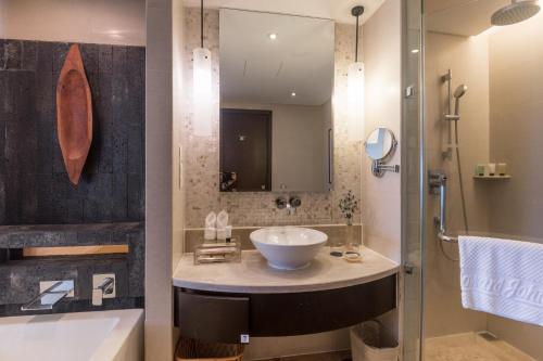 y baño con lavabo, espejo y bañera. en Howard Johnson Resort Sanya Bay en Sanya