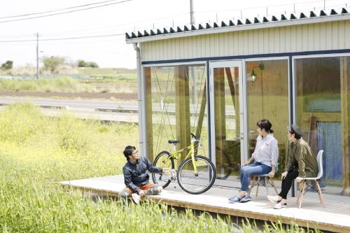 three women sitting on a porch of a house with a bike at COCORETO The Guesthouse Daikon Island in Matsue