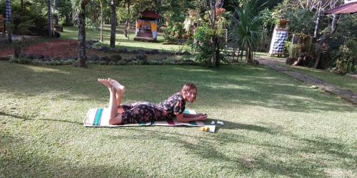 a woman laying on a towel on the grass at ESA di Kubu Homestay in Singaraja