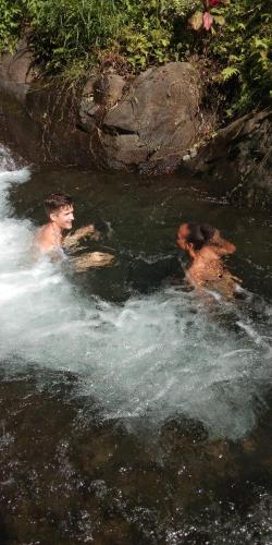 two men in the water in a river at ESA di Kubu Homestay in Singaraja