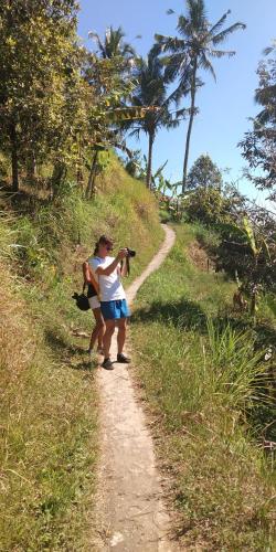 two people walking down a dirt path on a hill at ESA di Kubu Homestay in Singaraja