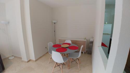 a table with white chairs and a red plate on it at Alojamiento Plaza Chirinos in Córdoba