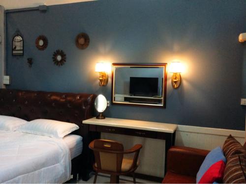 a bedroom with a bed and a desk with a mirror at Baan JaoKorKluay บ้านเจ้ากอกล้วย in Chiang Rai
