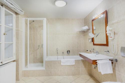 ein Bad mit einer Badewanne, einem Waschbecken und einer Dusche in der Unterkunft Boutique Hotel Constans in Prag