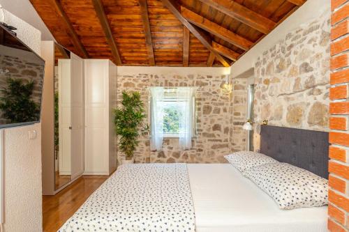 a bedroom with a bed and a stone wall at Villa Klacina in Goveđari