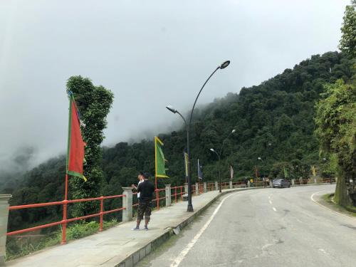 a man standing on a fence next to a road at Vamoose Soshing Homestay in Ravangla