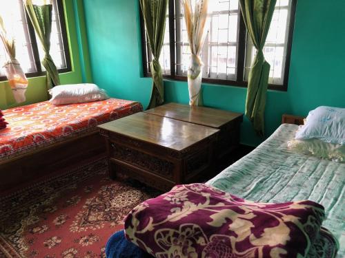 a room with two beds and a table and windows at Vamoose Soshing Homestay in Ravangla