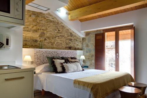 a bedroom with a bed and a stone wall at Numa Rúa Travesa in Santiago de Compostela