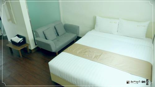 a hotel room with a bed and a chair at Residence Mumum Hotel in Busan