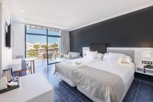 a hotel room with a large bed and a table at Hotel Mirador Papagayo by LIVVO in Playa Blanca