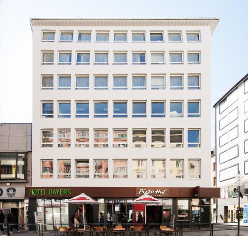 un gran edificio blanco con mesas delante en Hotel Bayer's en Múnich
