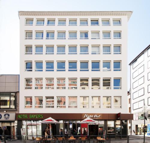 a large white building with tables in front of it at Hotel Bayer's in Munich