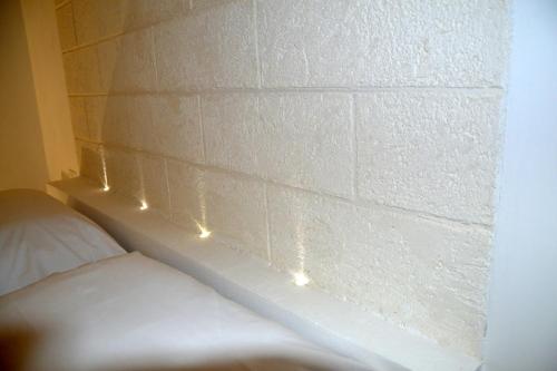 a brick wall with lights on it next to a bed at Quintessenza - Charme Rooms in Vieste