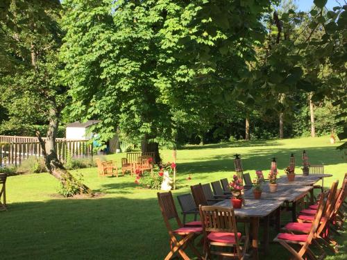 a long wooden table and chairs in a yard at Hotel L'Aunette Cottage in Chamant