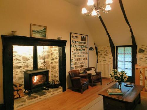 a living room with a fireplace and a chair and a table at La Maisonnette in Entraygues-sur-Truyère