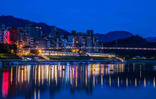a city lit up at night next to a body of water at Bitan Hotel in Xindian