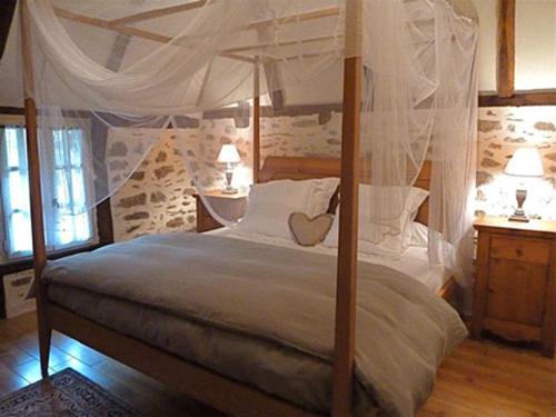 a bedroom with a canopy bed with white pillows at La Maisonnette in Entraygues-sur-Truyère