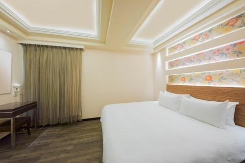 a hotel room with a bed and a desk at Bitan Hotel in Xindian