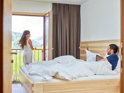 un hombre y una mujer en una habitación de hotel con una cama en Residenz Tirol, en Lechleiten