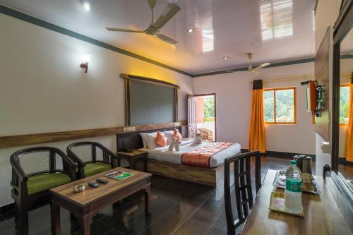 ein Schlafzimmer mit einem Bett und zwei Stühlen und einem Tisch in der Unterkunft Upavan Resort in Vythiri