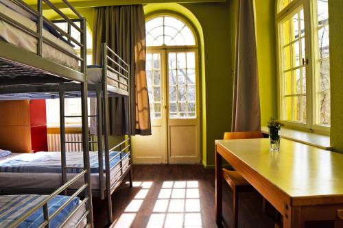 Zimmer mit Etagenbetten, einem Tisch und einem Schreibtisch in der Unterkunft Amstel House Hostel in Berlin